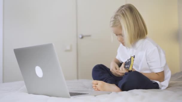 Distansutbildning på nätet. En skolpojke som lär sig spela ukulele på laptop hemma. — Stockvideo