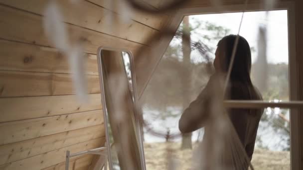 Guapa joven mirando en el espejo y admirándose a sí misma en casa de madera étnica.. — Vídeos de Stock