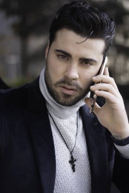 Mutlu ve baştan çıkarıcı genç başarılı iş adamı cep telefonuyla konuşuyor.