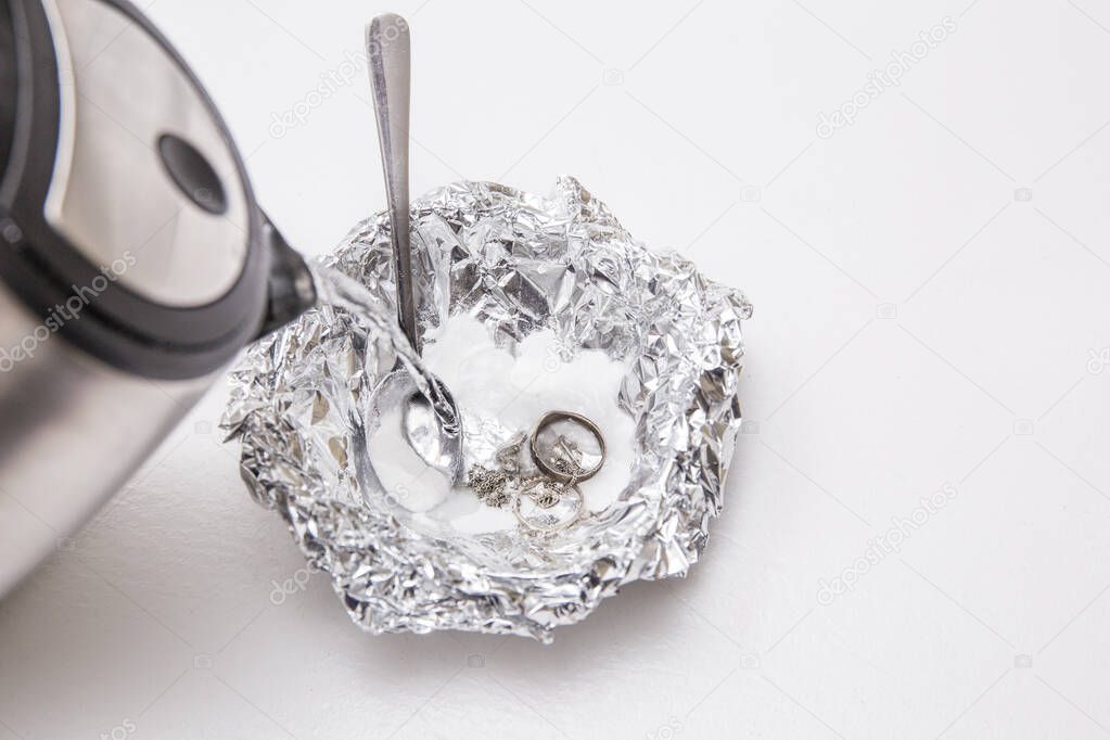 A solution of baking soda(Sodium bicarbonate) and warm water will remove the tarnish from silver when the silver is in contact with a piece of aluminium tin foil. Pouring hot water over silver.