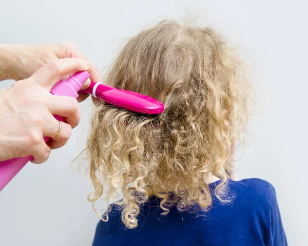 近距离观察母亲的手喷卷发香膏到女孩的头发上 以帮助梳理凌乱的卷发概念 室内最低灰度背景 — 图库照片