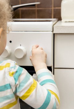 Sahipsiz çocukların oyun oynamalarını ve mutfak sobasının düğmelerini tek başına çevirmelerini yakından izleyin. Ev kavramında yangın tehlikesi.