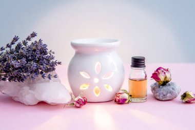 Beyaz seramik mum aromalı yağ yağı lambası ve kurutulmuş çiçekler modern pastel pembe ve mavi arka planda kristal jeojenler..