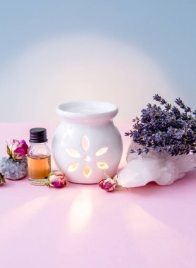 Beyaz seramik mum aromalı yağ yağı lambası ve kurutulmuş çiçekler modern pastel pembe ve mavi arka planda kristal jeojenler..