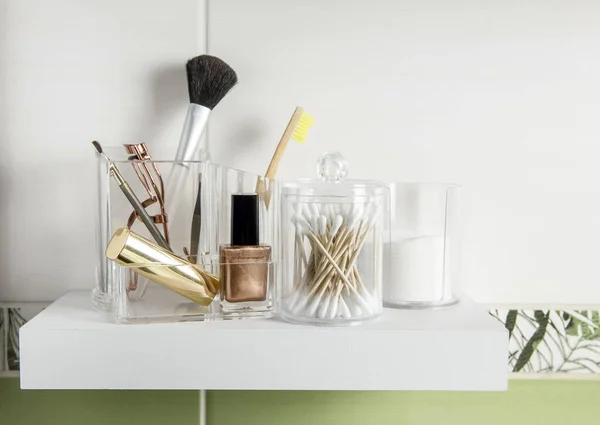 Make up products organizing concept. Beauty products in organizer container box on tidy way on minimalist shelf. Cotton pads stacked, Q-tips and make up brushes.