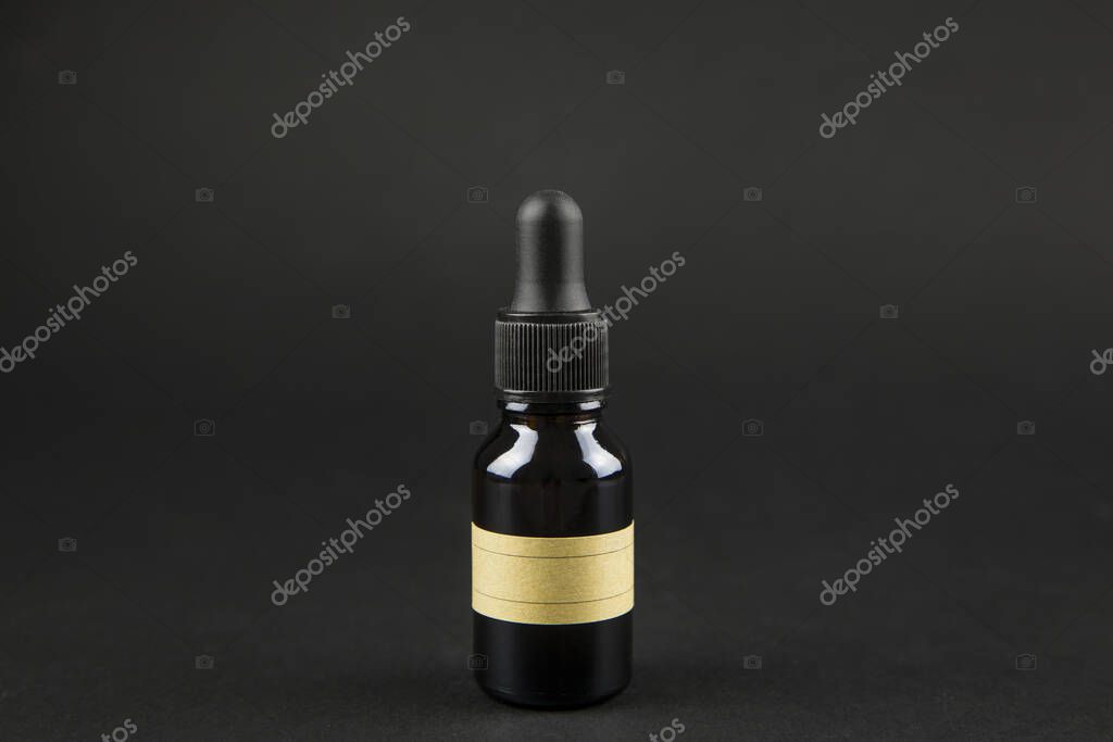 Brown pipette bottle on black background with brown blank label, fill in yourself.