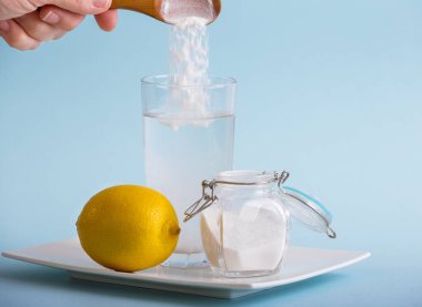 Su ve limon suyu ile içme bardağına el yapımı kabartma tozu sindirim sistemi konsepti için sağlık faydaları. Mavi arkaplan, boşluğu kopyala.