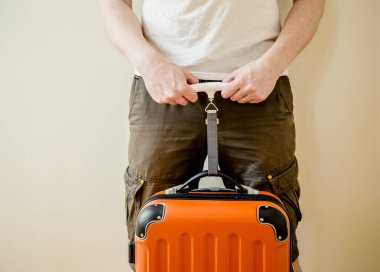 Erkek turist, havaalanı konseptinde aşırı kilolu bagajlardan kaçınmak için evde dijital bagaj terazisi kullanıyor. Yolculuk stresini azaltır.