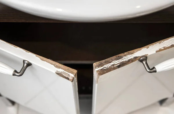 Su hasarlı yüksek parlak beyaz MDF banyo süs dolabı kapısı pervazlı. Nemli banyo durumu konsepti.