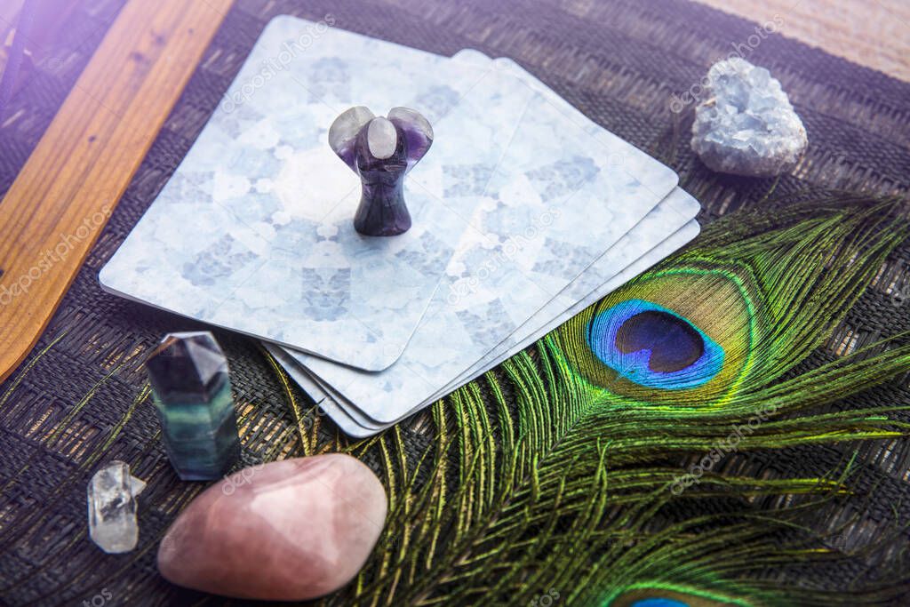 Deck with divination homemade Angel cards on black table, surrounded with semi precious stones crystals. Selective focus on amethyst crystal angel figurine.