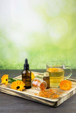 Calendula officinalis, marigold, ruddles, marigold veya Scotch marigold ahşap tepside farklı sağlık ürünleri, temel yağ, tentür, bitkisel çay, taze ve kurutulmuş çiçekler taze yeşil.