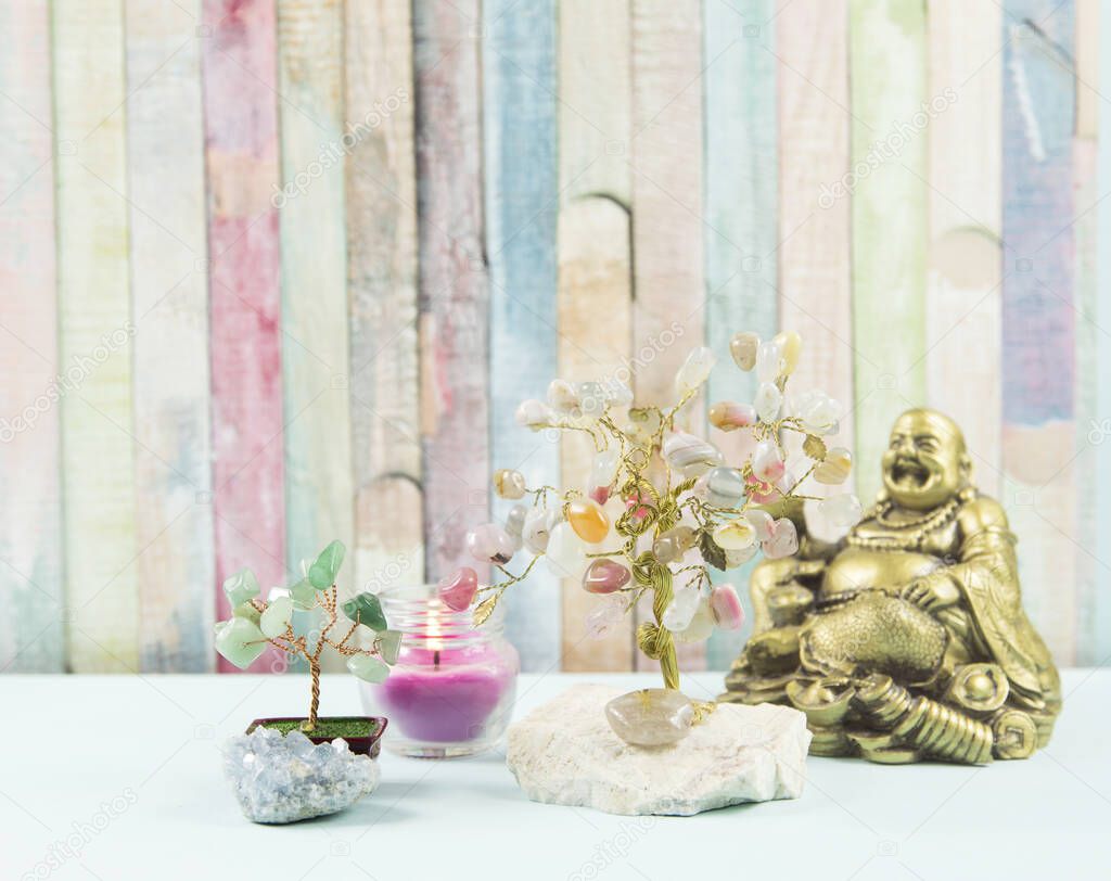 Zen background. Mental, body and soul balance, different spiritual objects Buddha figure, tree of happiness, money tree, candle, crystal cluster on table, painted colorful wooden background.