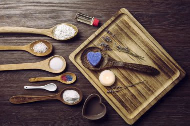 Ev kavramında köpüren banyo bombaları yapmak. Ahşap kaşıklardaki tüm malzemeler masada. Düz görünüm.