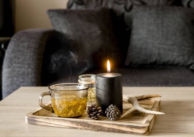 Minimalist İskandinav tarzı siyah renk ev dekoru kavramına yakından bakın. Buharda pişirilmiş bitki çaylı ahşap tepsi, aydınlatılmış siyah mum, geyik boynuzu, çam kozalağı..