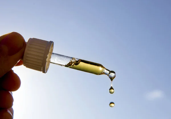 Güneşli bir günde güneşe ve mavi gökyüzüne karşı güzel bir D vitamini ile el ele tutuşan damlacık pipeti. D vitamini kışın güneş yokken sizi sağlıklı tutar..