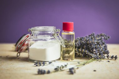 Zeytinyağı ve kabartma tozu temizleme konsepti. Ev yapımı doğal güzellik kozmetiği. Kabartma tozu ve zeytin yağlı bir şişe ile kavanoz mor arka planda lavanta buketi..