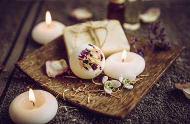 Doğal ahşap tepside çeşitli rahatlatıcı banyo ürünleri: kremalı banyo bombası, sabun ve aroma yağı şişeleri. Ev kavramında rahat rahatlama.