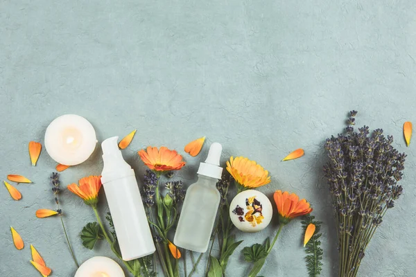 Organic plant based cosmetics concept. Top view of various herbs plants and beauty product containers on vintage blue background.