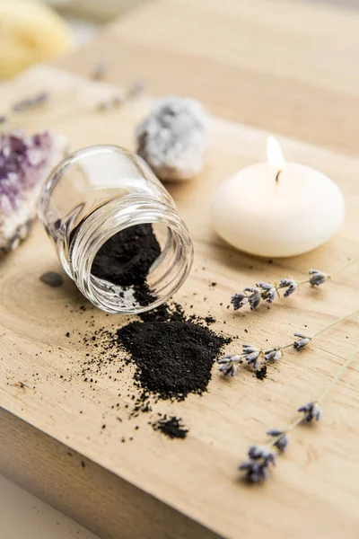 Raw activated charcoal powder in beauty products concept. Lot of copy space. Spa candle burning.