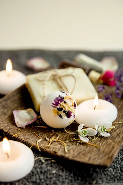 Various relaxation bath products on natural wood tray: creamy bath bomb, bar of soap and aroma oil bottles. Cozy relaxation at home concept.