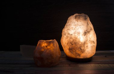 Elektriksel Himalaya pembe kaya tuzu lambası yanıyor ve çay mumu ışığı mum tutacağı koyu siyah arka planda, stüdyoda. Rahatlatıcı ruh hali konsepti. Boşluğu kopyala.