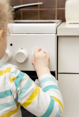 Sahipsiz çocukların oyun oynamalarını ve mutfak sobasının düğmelerini tek başına çevirmelerini yakından izleyin. Ev kavramında yangın tehlikesi.