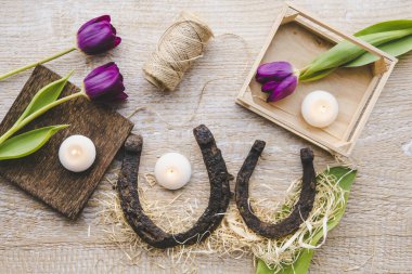 Beyaz küçük mumlarla süslenmiş, hafif tahta arka planda iki paslı, küçük ve büyük at nalının düz manzarası vardı. At nalı evde iyi şans ve korunma sembolüdür. Vastu Shastra konsepti.
