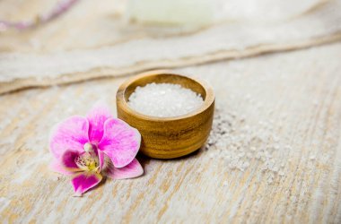 Orkide çiçekli çilek banyosu bombası ve açık ahşap arka planda aroma tuzu ve fotokopi alanı. Terapi konsepti. Ev kavramında rahatlama.