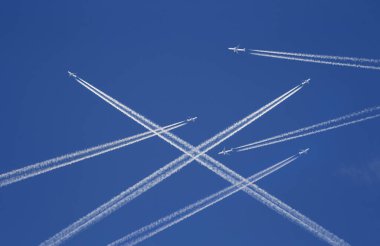 A lot of passenger airplanes on the air, busy air traffic, traveling high season starts concept. White planes against blue sky.  Photo manipulation. clipart