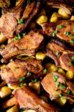 Ev yapımı güzel yemek, fırında domuz pirzolası ve yeşil soğanla kaplanmış fırında sarı patates. Siyah arkaplan.