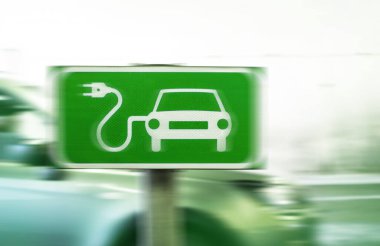 Elektrikli araba şarj etme işareti. Arka planda bulanık araba var. Yeşil enerji kavramı. 