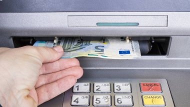 Bankamatik makinesinden para alan bir kadın eli. Maaş konsepti.