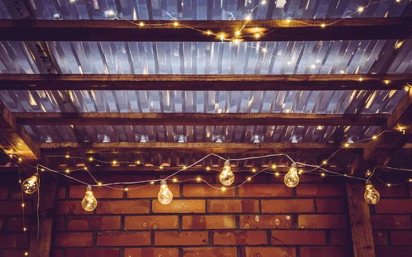 Different garden party lights on terrace transparent ceiling, micro leds and bulbs on string at night.