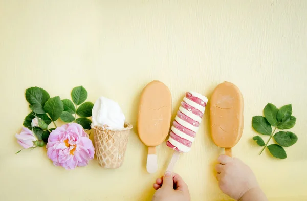黄色の背景に多くの異なるタイプと色のアイスクリームの多様性 子供たちはアイスクリーム フラットレイを取って手 — ストック写真