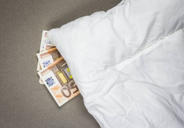 Hiding money under the pillow. 50 euro bank notes under the white pillow. clipart