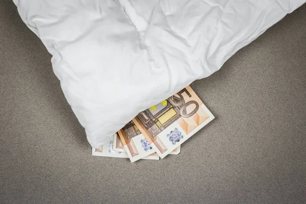 Hiding money under the pillow. 50 euro bank notes under the white pillow.