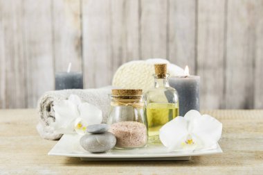 Güzellik salonunun temelinde arka plan minimumu var. Hafif ahşap arka planda banyo ürünleri. Ahenkli lüks yaşam tarzı konsepti. Havlu, mum, banyo tuzu, kokulu masaj yağı..