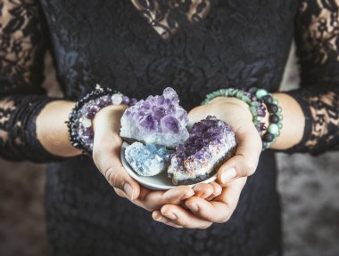 Healer woman holding different crystal clusters( amethyst, celestite) in palms hands. Close up view, using working with crystals concept. clipart