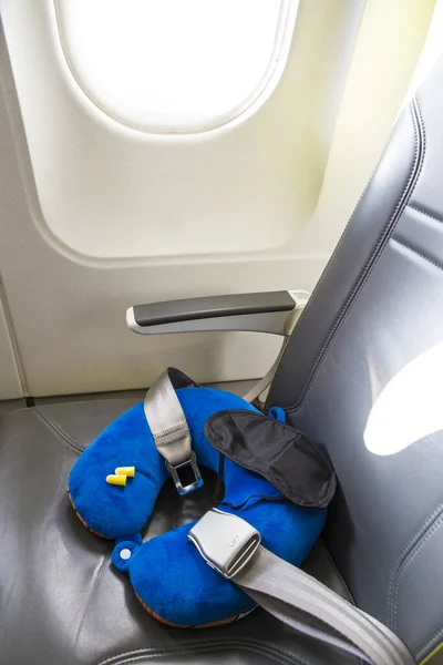 Blue soft traveling pillow, noise removing ear plugs and sleeping mask, in plane cabin on passenger seat, comfortable cozy traveling concept, composition.