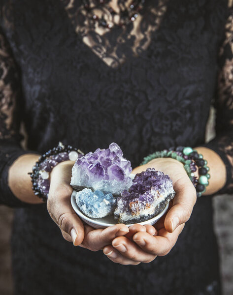 Healer woman holding different crystal clusters( amethyst, celestite) in palms hands. Close up view, using working with crystals concept.