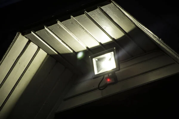 Outdoor LED lamp with motion sensor working above the door that detects movement. Safety concept.
