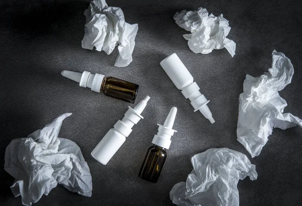 Nasal spray dipendence concept. When using DNSs for too long it causes rather than prevents congestion, rhinitis medicamentosa. Lot of empty used nasal spray dispenser bottles scattered on table.
