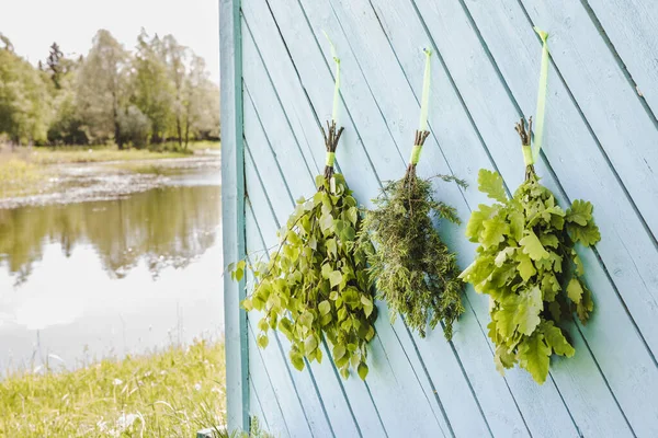 新鮮なオーク ジュニパー オークの木のサウナは 美しい自然湖でサウナの家の壁にぶら下がって乾燥させます 伝統的なフィンランド式サウナのコンセプト — ストック写真
