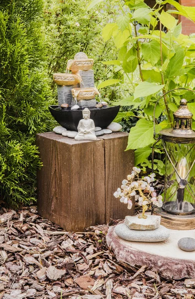 Ağaçlar ve çalılar arasında meditasyon yapan Buda heykeli olan küçük bir ev bahçesi çeşmesi. Özel zen bahçesi konsepti.
