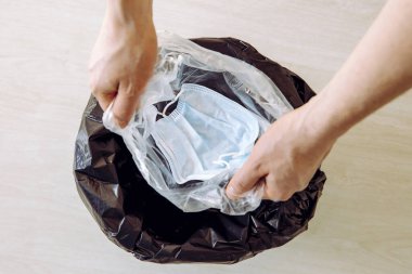 Tek kullanımlık tıbbi maske takıyor. Virüsün maskeden çöp tenekesine ve insanlara bulaşmasını önlemek için bir kerelik plastik poşete koyup çöpe atıyorlar.. 