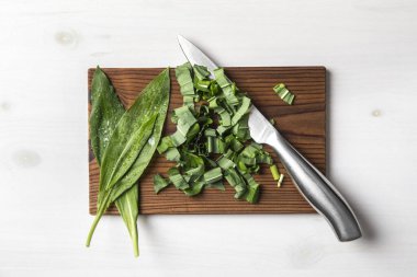 Vahşi sarımsak, Ramson, Buckram, geniş yapraklı sarımsak, ahşap sarımsak, ayı pırasası veya ayının sarımsak kesimi olarak bilinen ursinum yaprakları kahverengi doğal kesim tahtasının üzerinde..