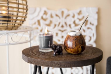 Yerba mate çay kabağı, metal bombilla pipetli ve fil heykelciği modern oturma odasındaki küçük masada doğuya ait detaylarla..