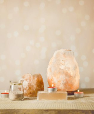 Himalaya sabun barı, pembe kaya tuzu lambası yanıyor ve tuz mum tutacağı yanıyor, içinde mum yanıyor, kavanoz içinde tuz taneleri var, arka planda, stüdyoda. Sakinleştirici zen ruh hali konsepti.