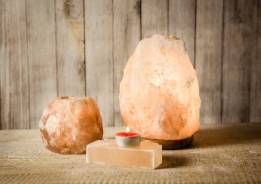Himalaya sabun barı, pembe kaya tuzu lambası aydınlatmalı ve tuzlu mum tutacağı, içinde mum yanan, ahşap arka planda tuz tanecikli kavanoz, stüdyo. Sakinleştirici zen ruh hali konsepti.