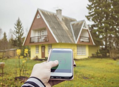 Kırsal ev kapısını açmak / kapatmak için akıllı telefon uygulamasında uzaktan elle kilidi aç / kilitle tuşuna basın. Modern yaşam tarzı teknoloji kavramı.